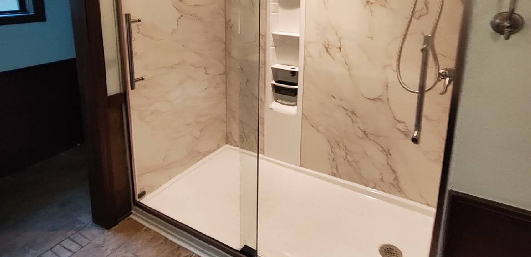 Modern shower area with glass door and marble walls.