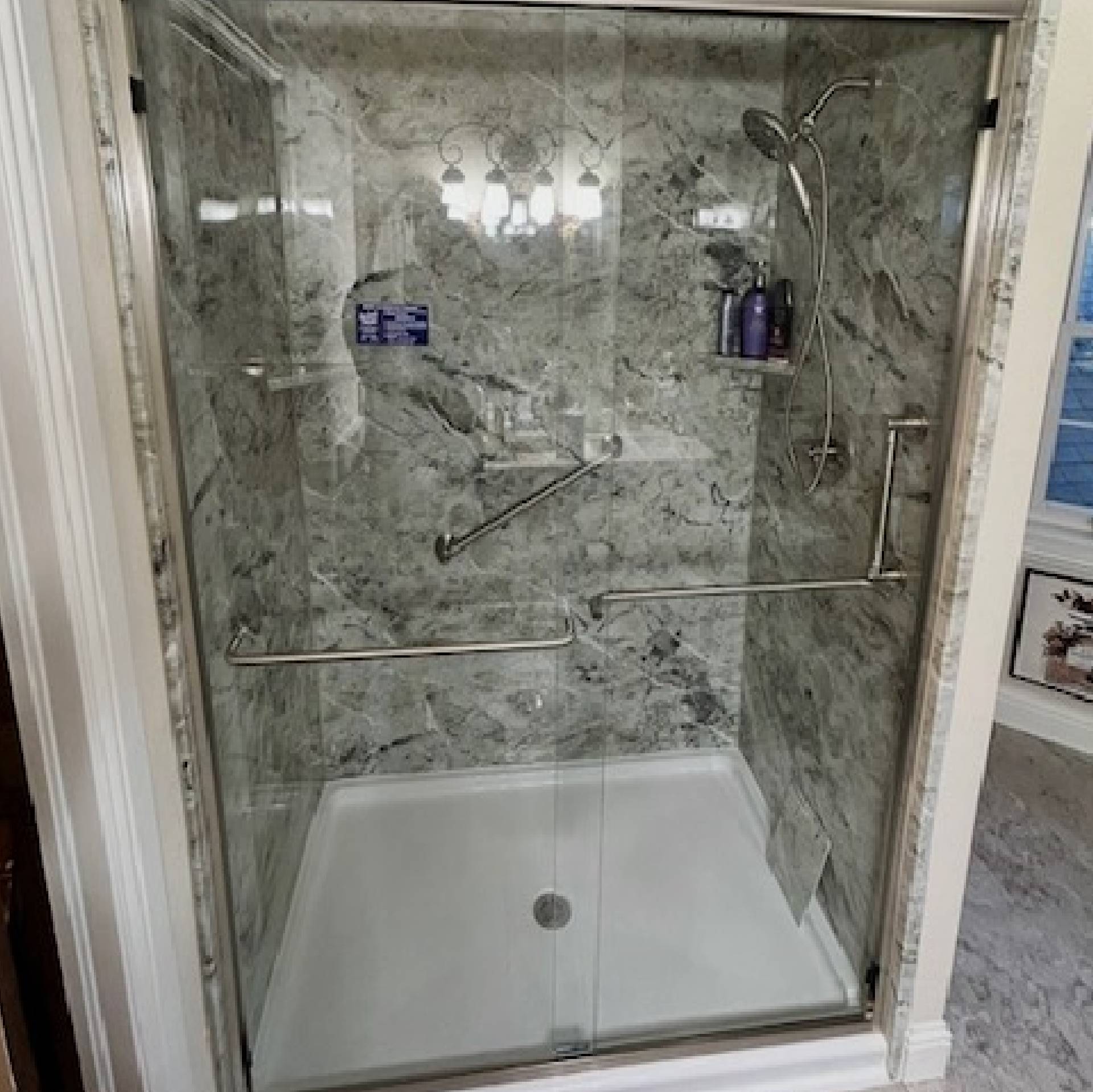 Modern shower with glass door and marble tiles.