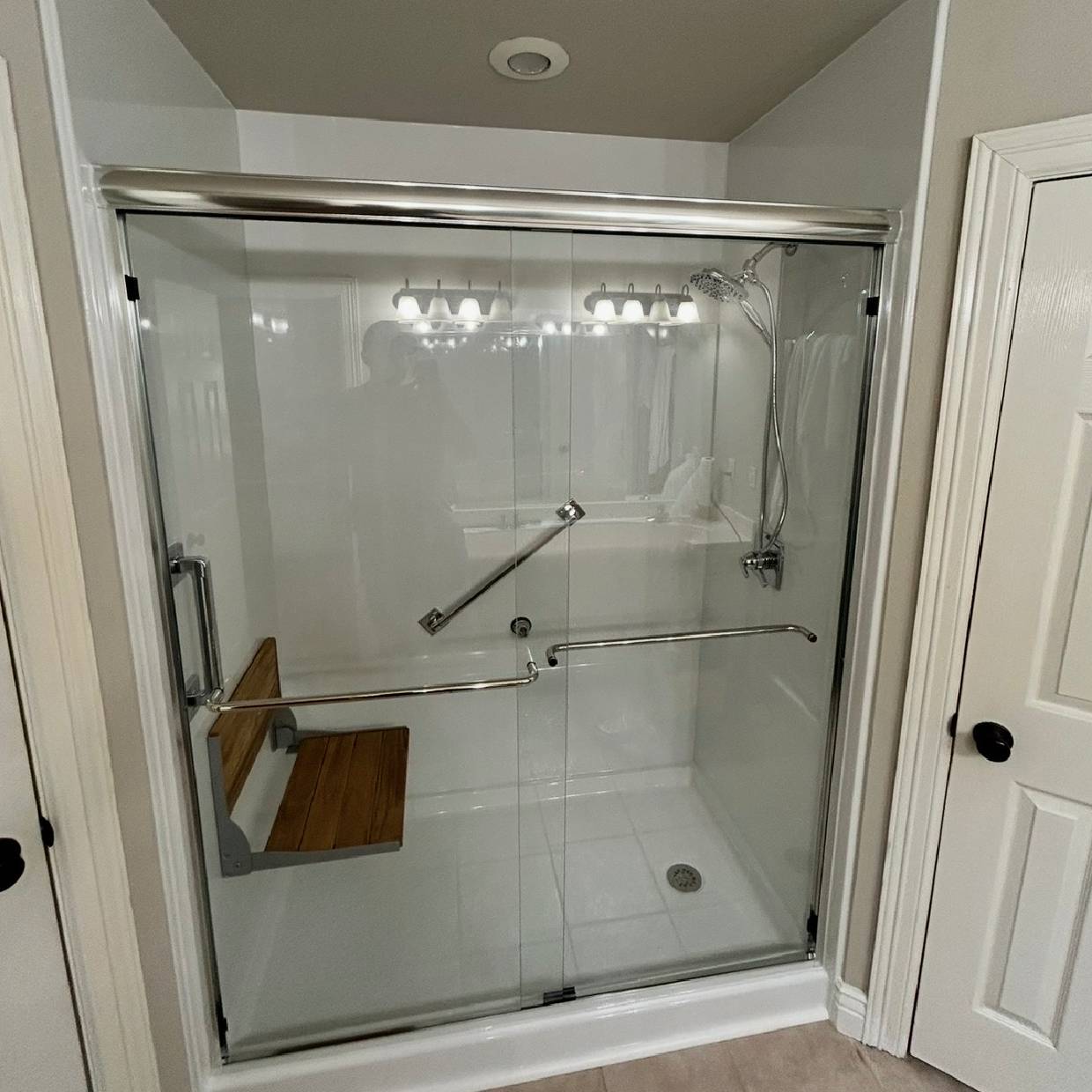 Modern accessible shower with glass doors and grab bars.