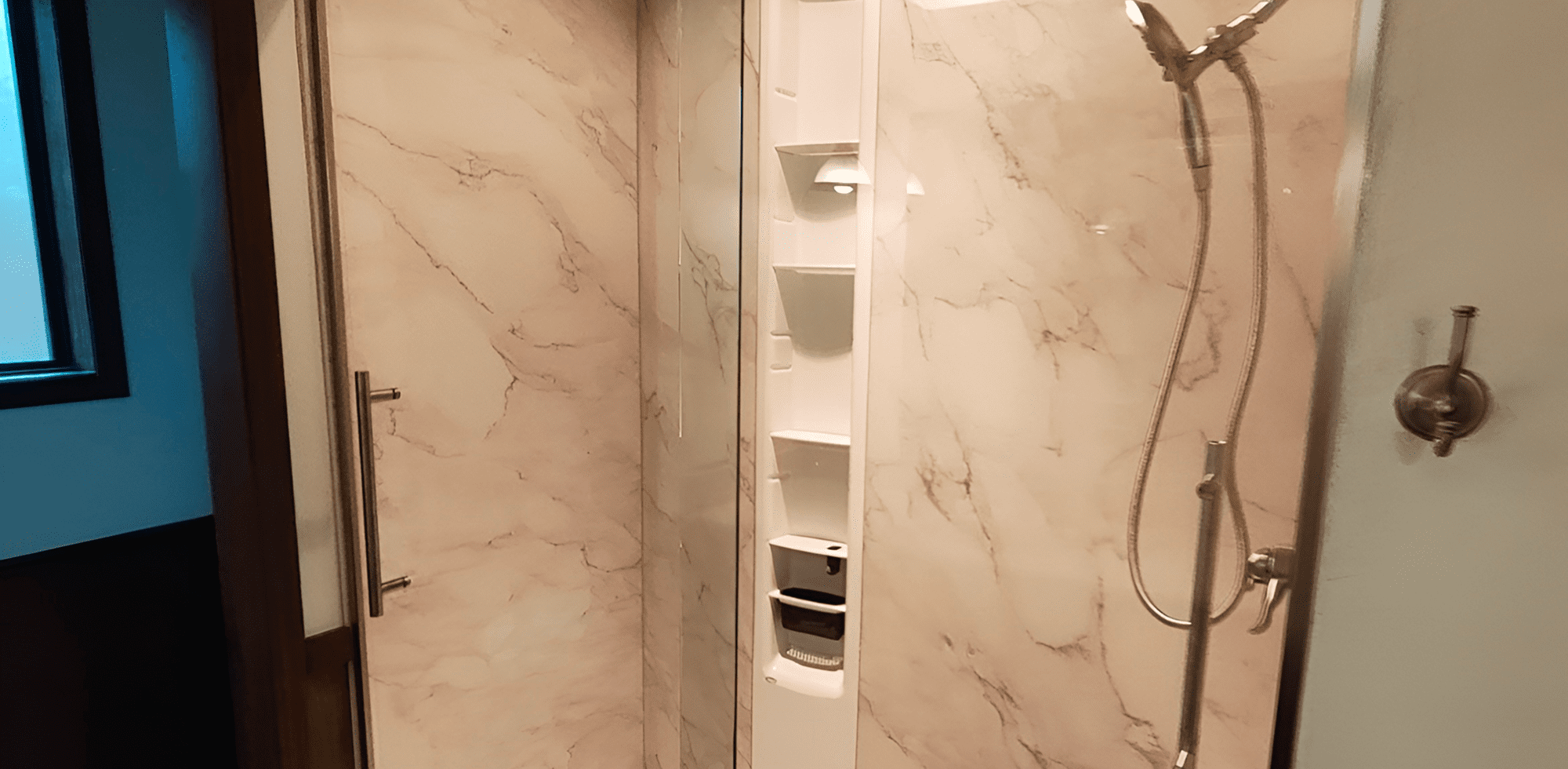 Modern shower with built-in shelves and marble walls.