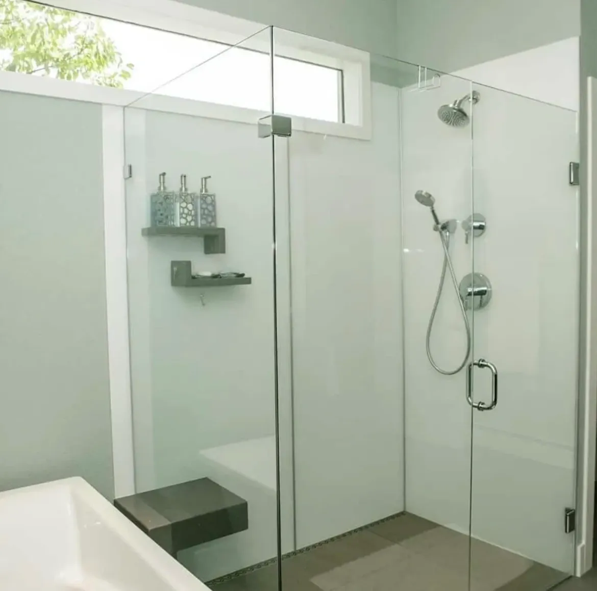 Modern bathroom with glass shower enclosure and floating shelves.