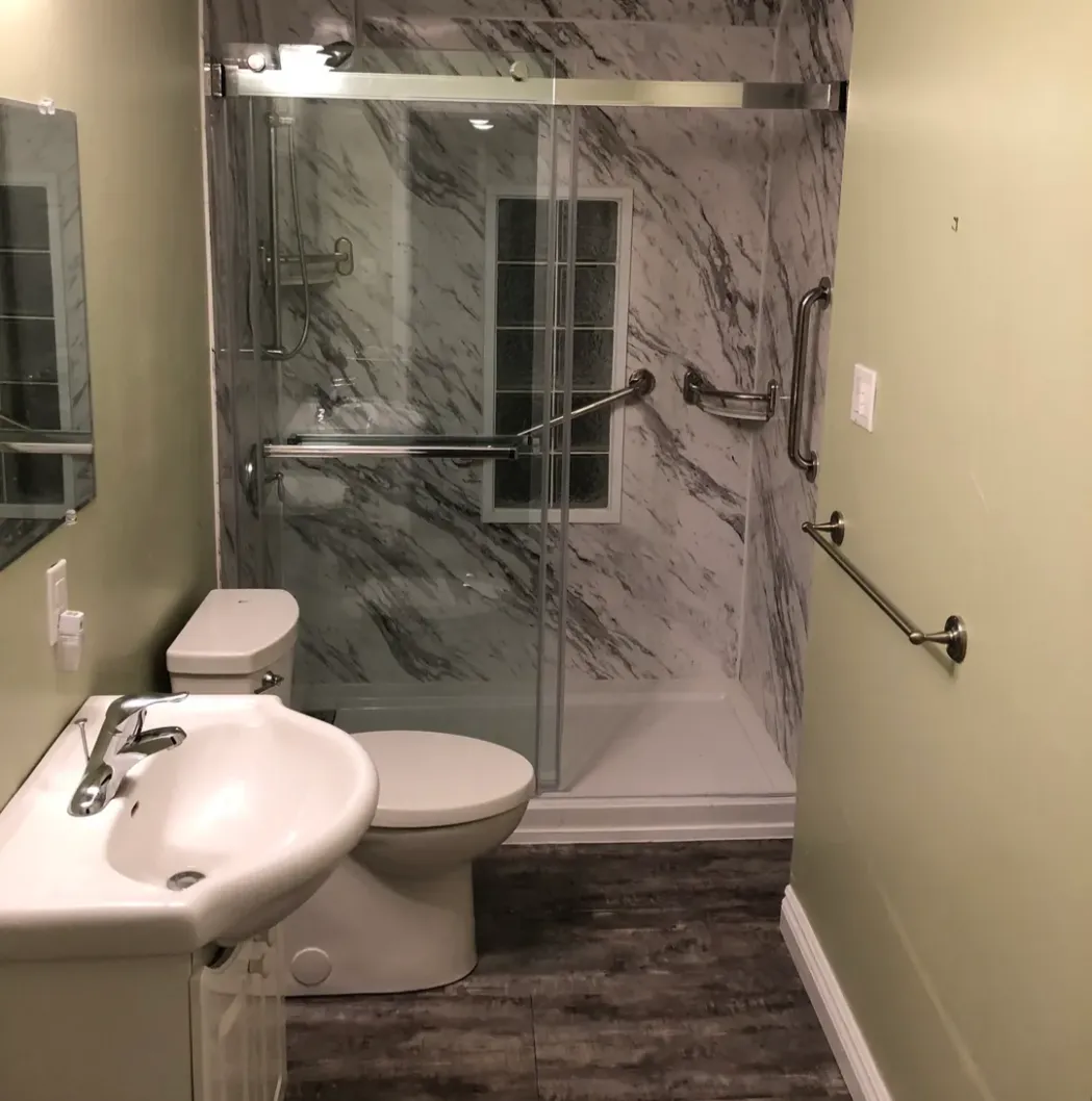 Compact bathroom with marble shower and wall-mounted fixtures.
