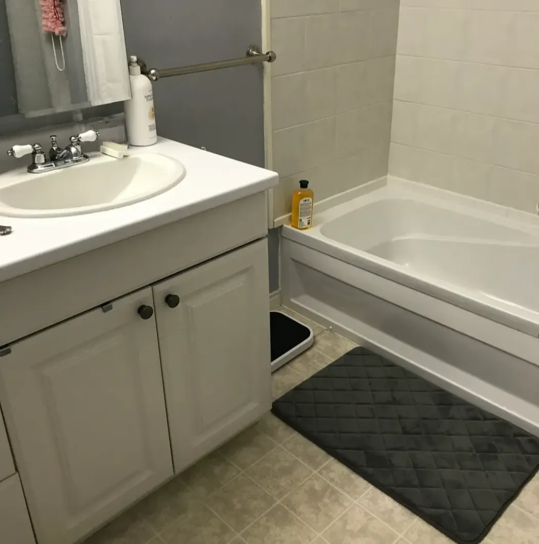 Small bathroom with white vanity and bathtub.