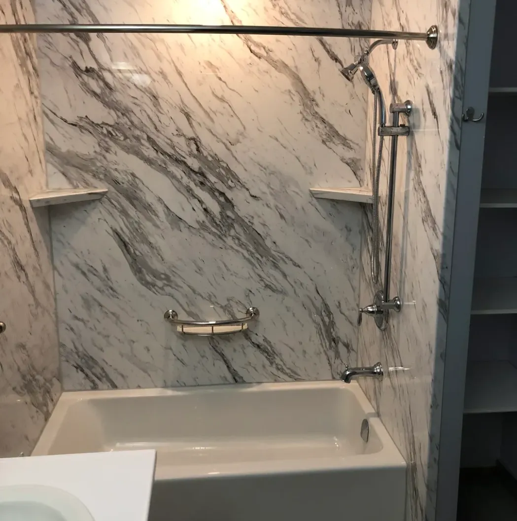 Modern bathroom with marble walls and a white bathtub.