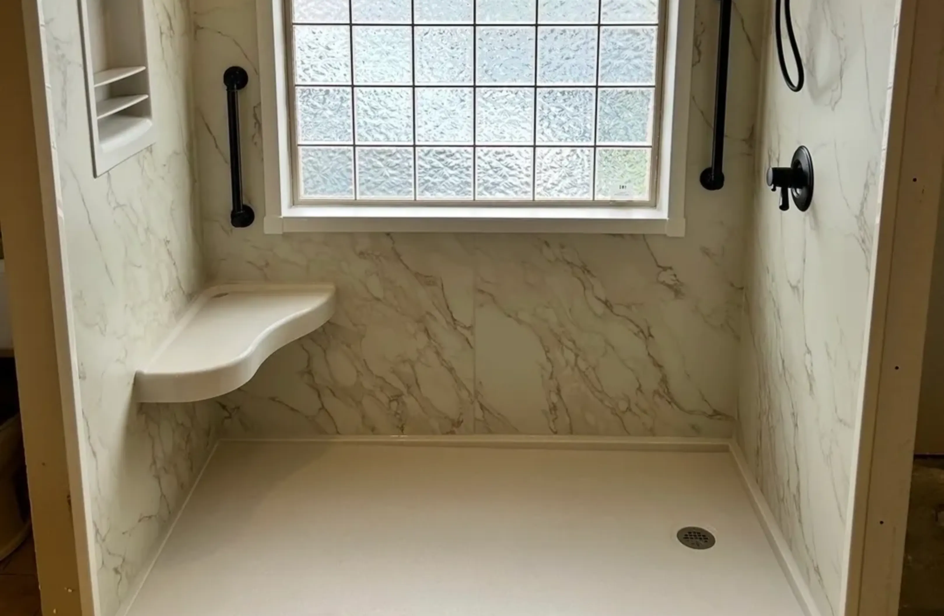 Minimalist shower area with marble walls and a frosted window.