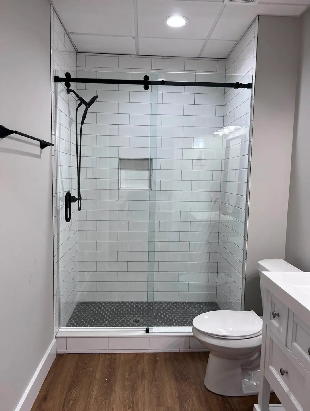 Modern bathroom with glass shower enclosure and white subway tiles.
