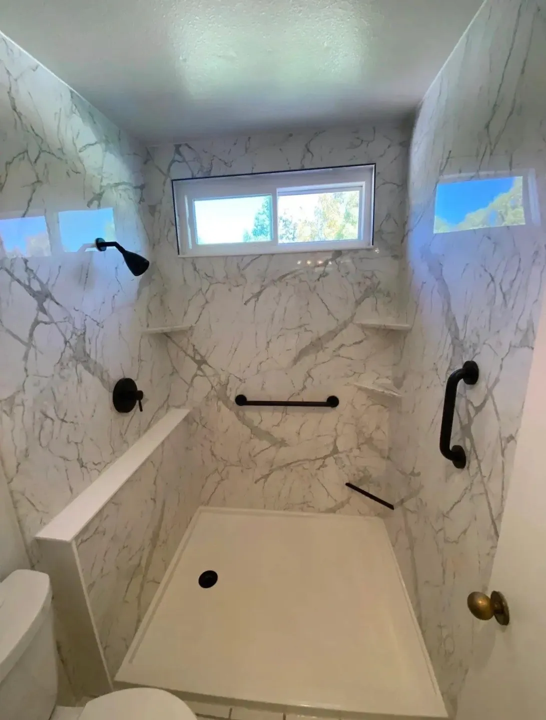 Spacious walk-in shower with marble walls and built-in seating.