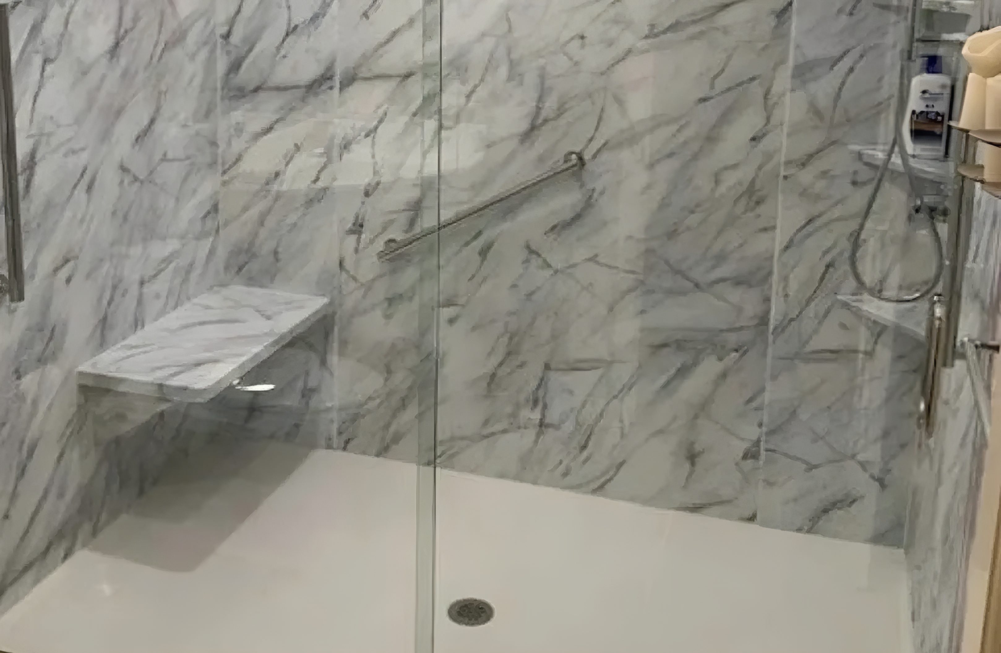 Modern shower with marble walls and glass door.