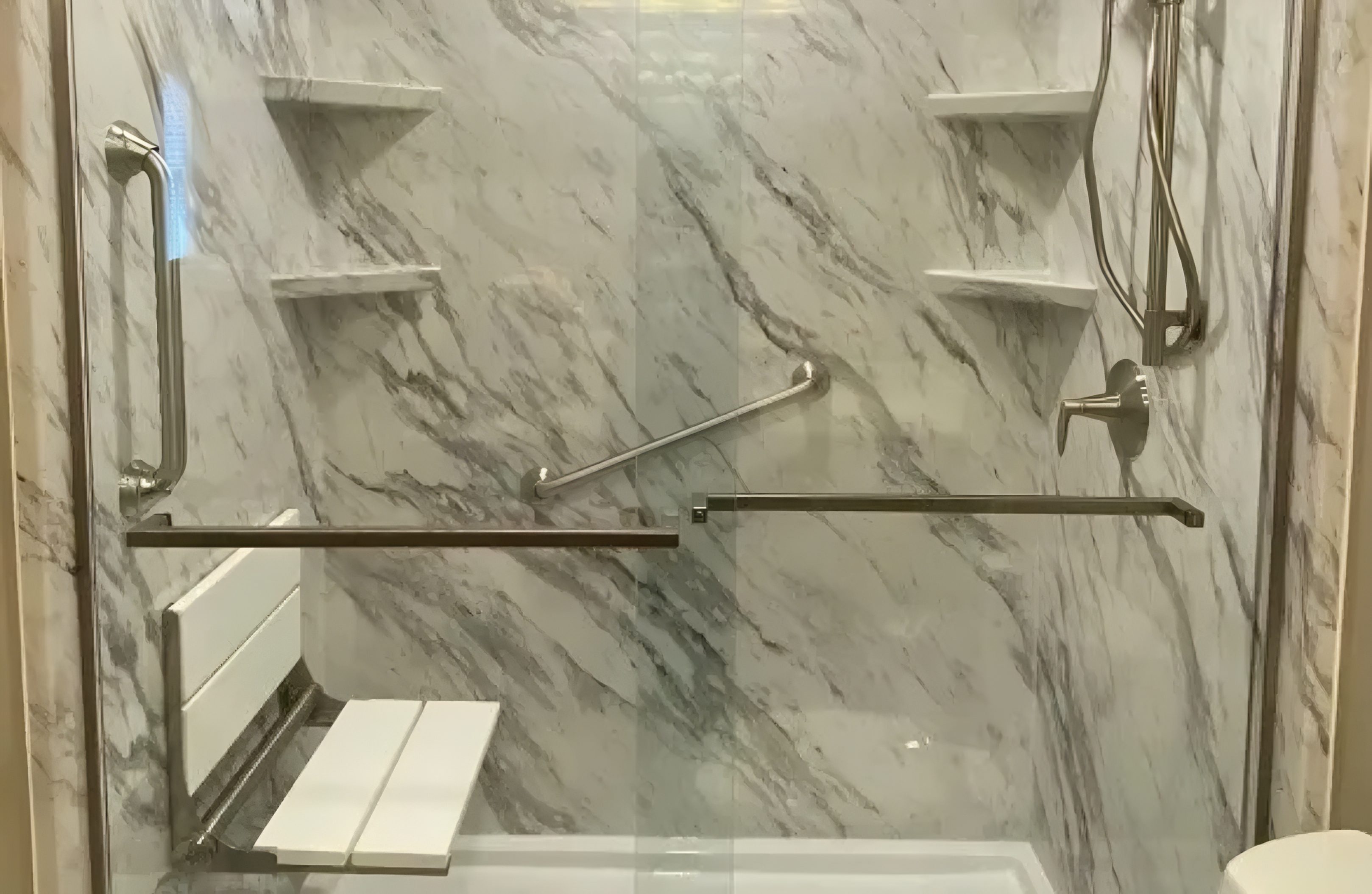 Elegant marble shower with built-in shelves and a bench.