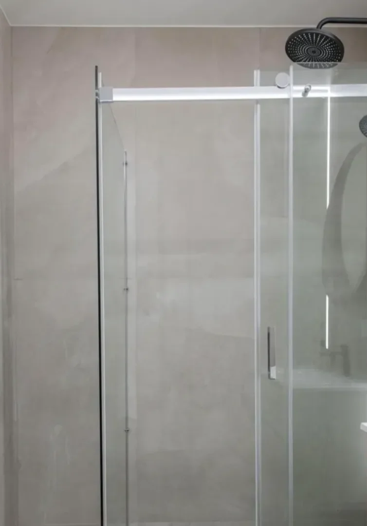 Modern minimalist bathroom with glass shower enclosure and rain showerhead.