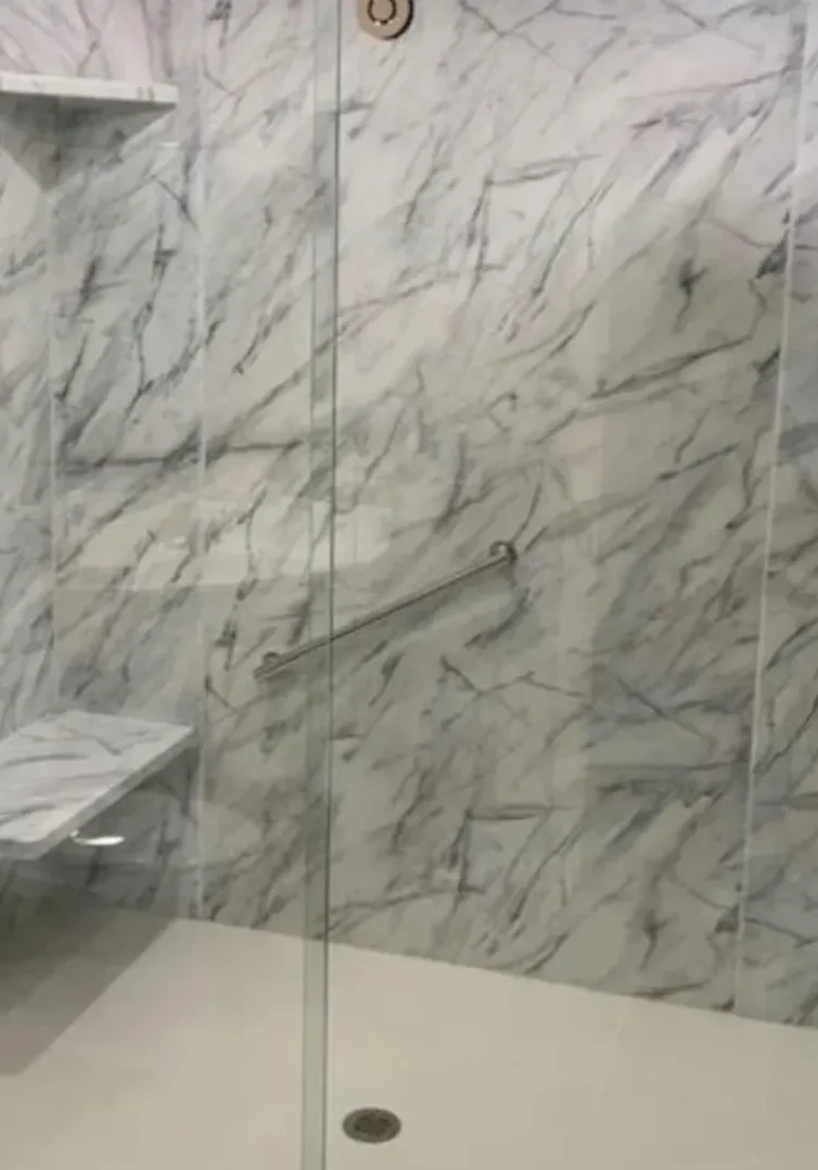 Modern shower with marble walls and glass door.
